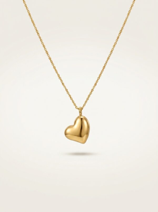A close up of a gold plated heart necklace on black velvet display