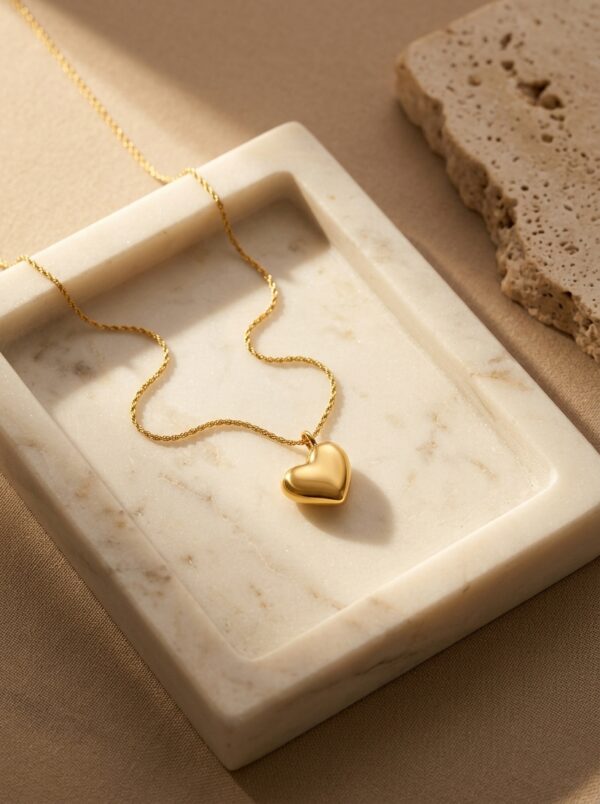 A close up of a gold plated heart necklace on black velvet display