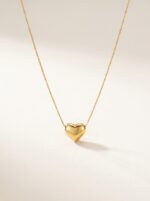 A delicate gold plated heart necklace on a black velvet display
