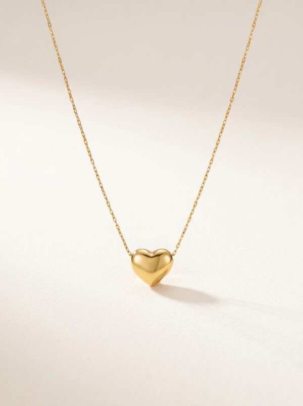 A delicate gold plated heart necklace on a black velvet display