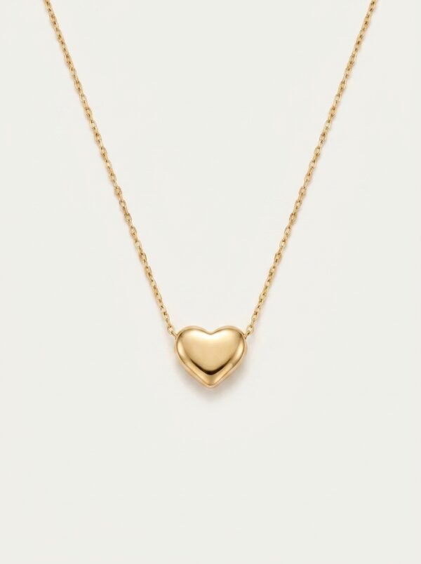 A delicate gold plated heart necklace on a black velvet display