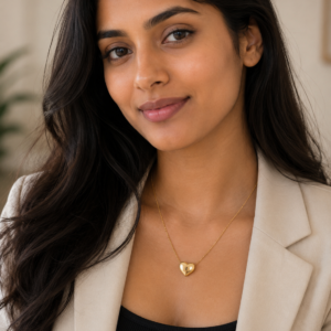 A delicate gold plated heart necklace on a black velvet display