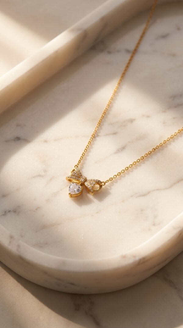 Close up of gold plated heart necklace with bow charm