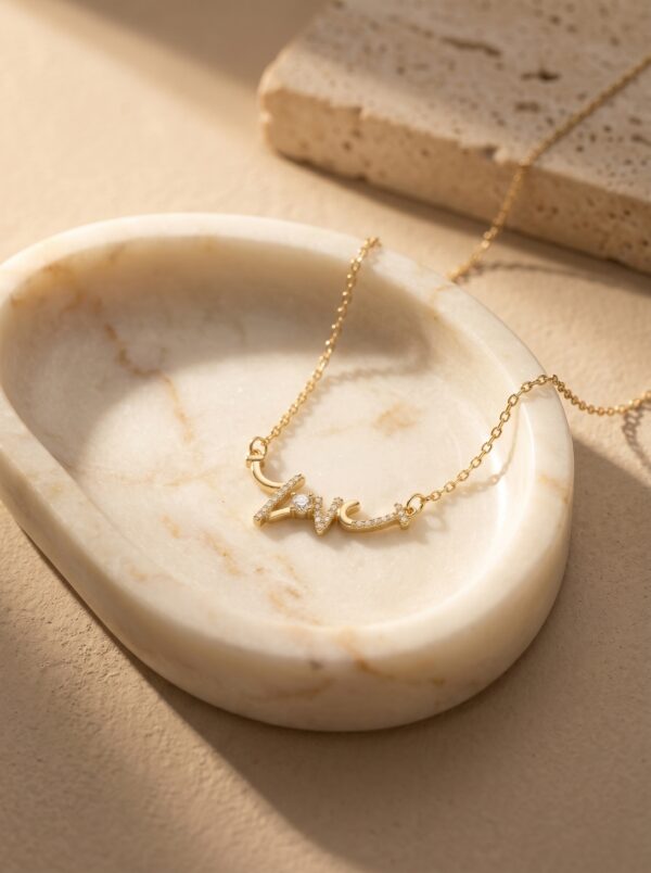 Model wearing a gold plated heart necklace with script detail