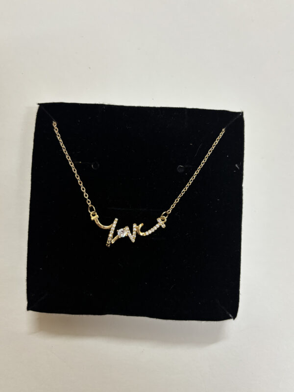 Model wearing a gold plated heart necklace with script detail