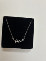 Woman wearing delicate silver love script necklace