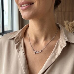 Silver love script necklace on white background