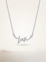 Silver love script necklace on white background