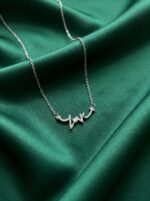 Silver love script necklace on white background