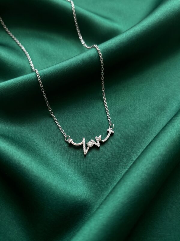 Silver love script necklace on white background