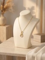 A delicate gold plated necklace resting on a marble tray