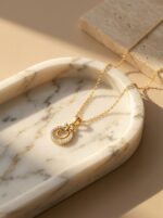 Close up of the gold plated necklace with a circular pendant on a black stand