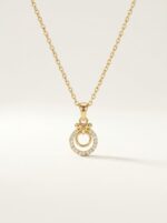 Close up of the gold plated necklace with a circular pendant on a black stand
