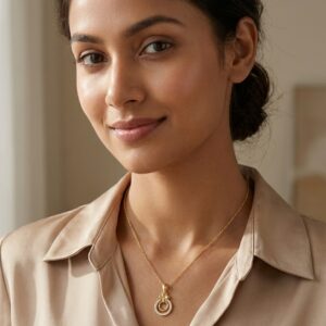 Close up of the gold plated necklace with a circular pendant on a black stand