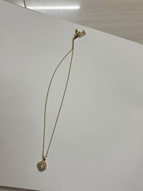 Close up of gold plated pendant with stone detailing on black velvet box