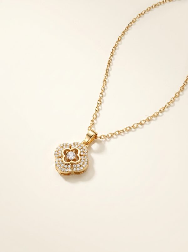 Gold plated pendant with clover motif on white surface