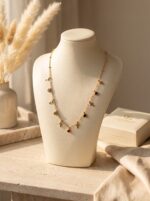Model wearing a delicate gold plated necklace with cross and gem charms