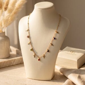 Model wearing a delicate gold plated necklace with cross and gem charms