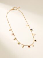 Multi-colored gem and cross charm gold plated necklace on display