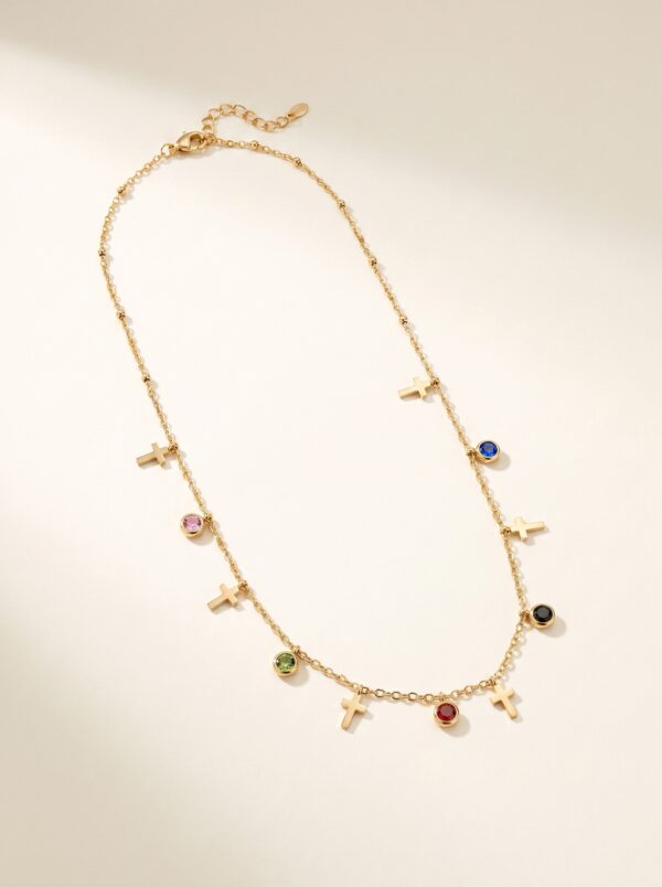 Multi-colored gem and cross charm gold plated necklace on display