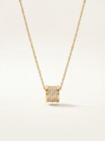 Close up of gold plated necklace with cylinder pendant