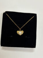 Woman wearing a delicate gold plated heart necklace with mother of pearl inlay