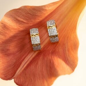 Two sparkling crystal hoop earrings resting on a flower petal
