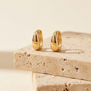 Small gold hoop earrings on stone background
