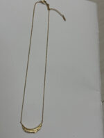 Close up of the Crescent Moon Golden Necklace resting on a black velvet display