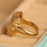 Adjustable band of a gold plated knot ring showing intricate detail in a teal jewelry box