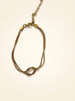 Gold knot bracelet resting on stone