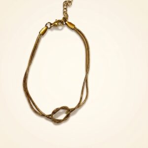 Gold knot bracelet resting on stone