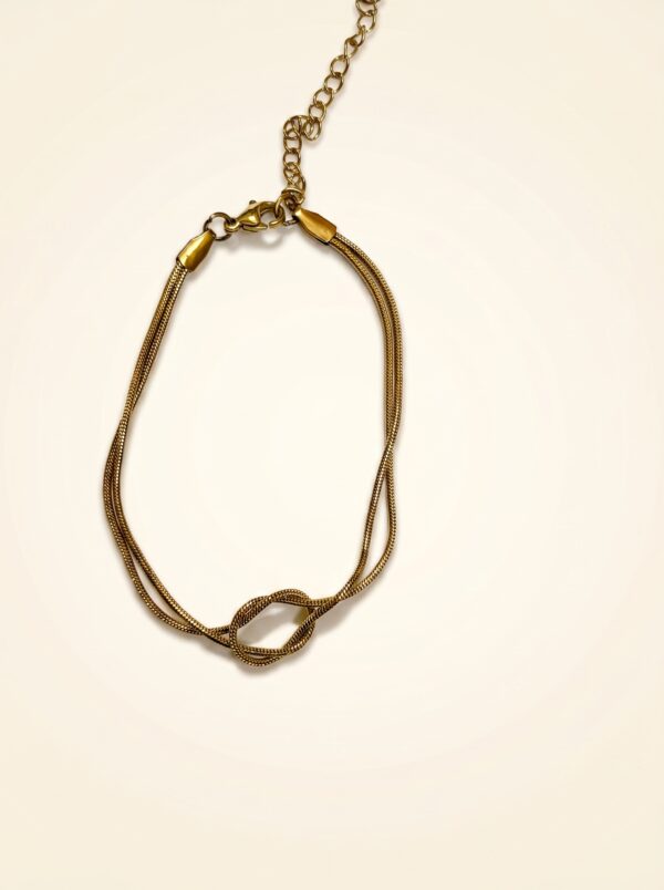 Gold knot bracelet resting on stone