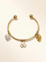 Close up of a gold plated kada featuring a clover floral charm and pearl