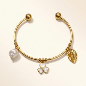 Close up of a gold plated kada featuring a clover floral charm and pearl