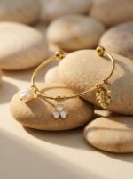 A woman wearing a stylish gold plated kada with a floral charm on her wrist