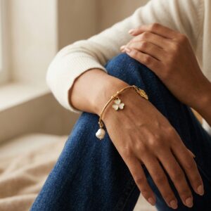 Elegant gold plated kada with a pearl and floral charm on a neutral background