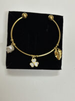 Elegant gold plated kada with a pearl and floral charm on a neutral background