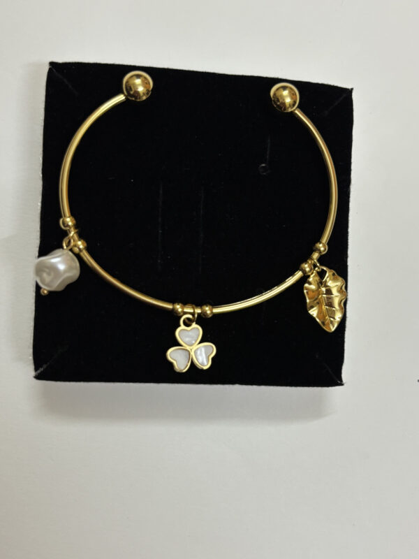 Elegant gold plated kada with a pearl and floral charm on a neutral background