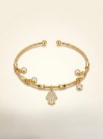 The Hamsa Protection Golden Bracelet resting on natural river stones