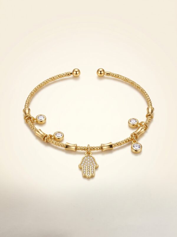 The Hamsa Protection Golden Bracelet resting on natural river stones