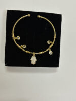 Close up of the Hamsa Protection Golden Bracelet on a cream background