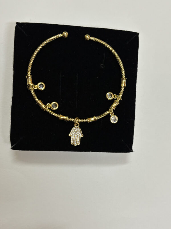 Close up of the Hamsa Protection Golden Bracelet on a cream background