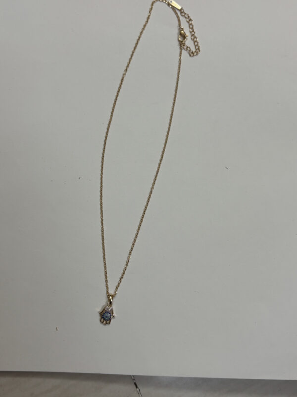 Close up of the Hamsa hand pendant detailing the blue and white stone inlay