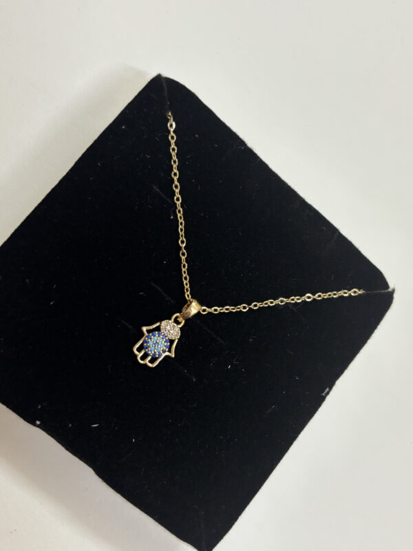 A delicate gold chain featuring a Hamsa hand pendant with blue and white stones