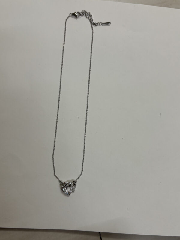 Studio shot of the Intertwined Heart Necklace on a soft cream background