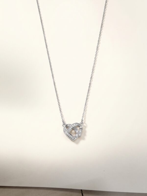 Flat lay of the Intertwined Heart Necklace on a white surface