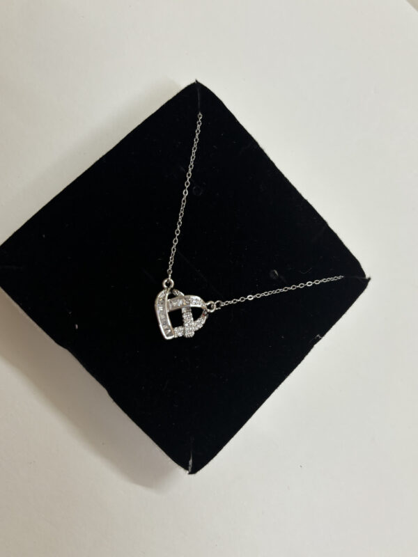 Flat lay of the Intertwined Heart Necklace on a white surface