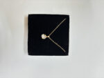 Golden necklace with mother of pearl center on marble tray