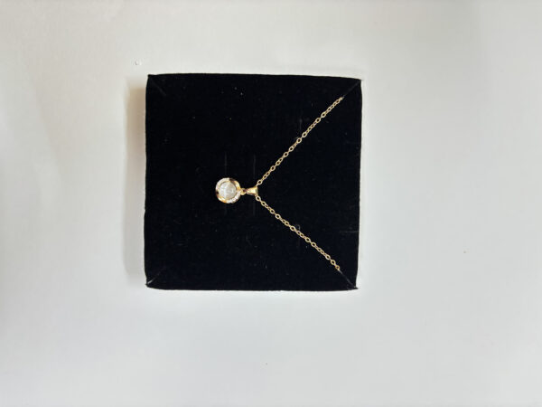 Golden necklace with mother of pearl center on marble tray